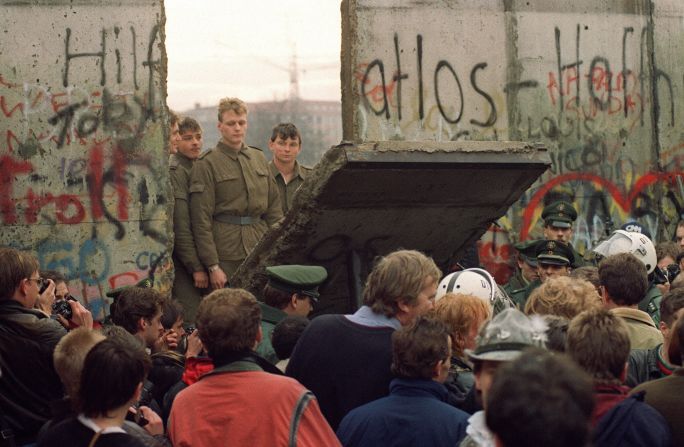 Ciudadanos de Berlín Occidental frente al Muro mientras guardias de Alemania del Este demuelen una sección de la barrera el 11 de noviembre de 1989.