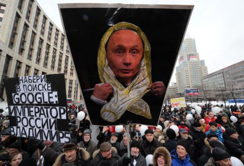 Protesters hold banners mocking Russian Prime Minister Vladimir Putin.