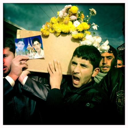 A funeral procession takes place in Dar Kabir, Homs, for "Malik," killed by government forces. His younger brother holds a photograph of Malik in his hands.