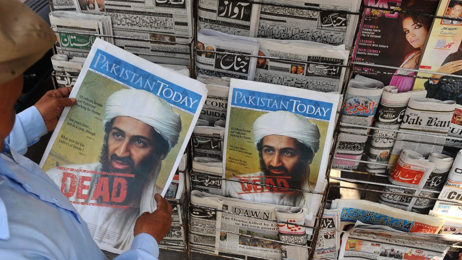 A Pakistani man reads a newspaper displaying news of the death of Osama bin Laden at a stall in Lahore on May 3, 2011.