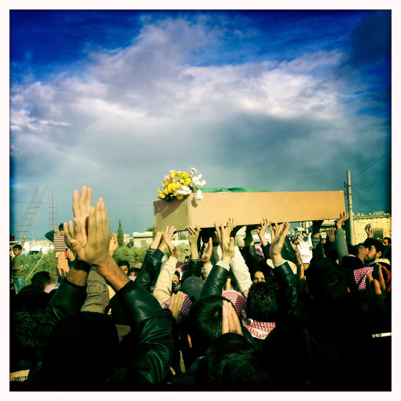 Mourners raise their hands at the funeral procession for "Malik," who was shot by government forces in Dar al-Kabira in Homs.