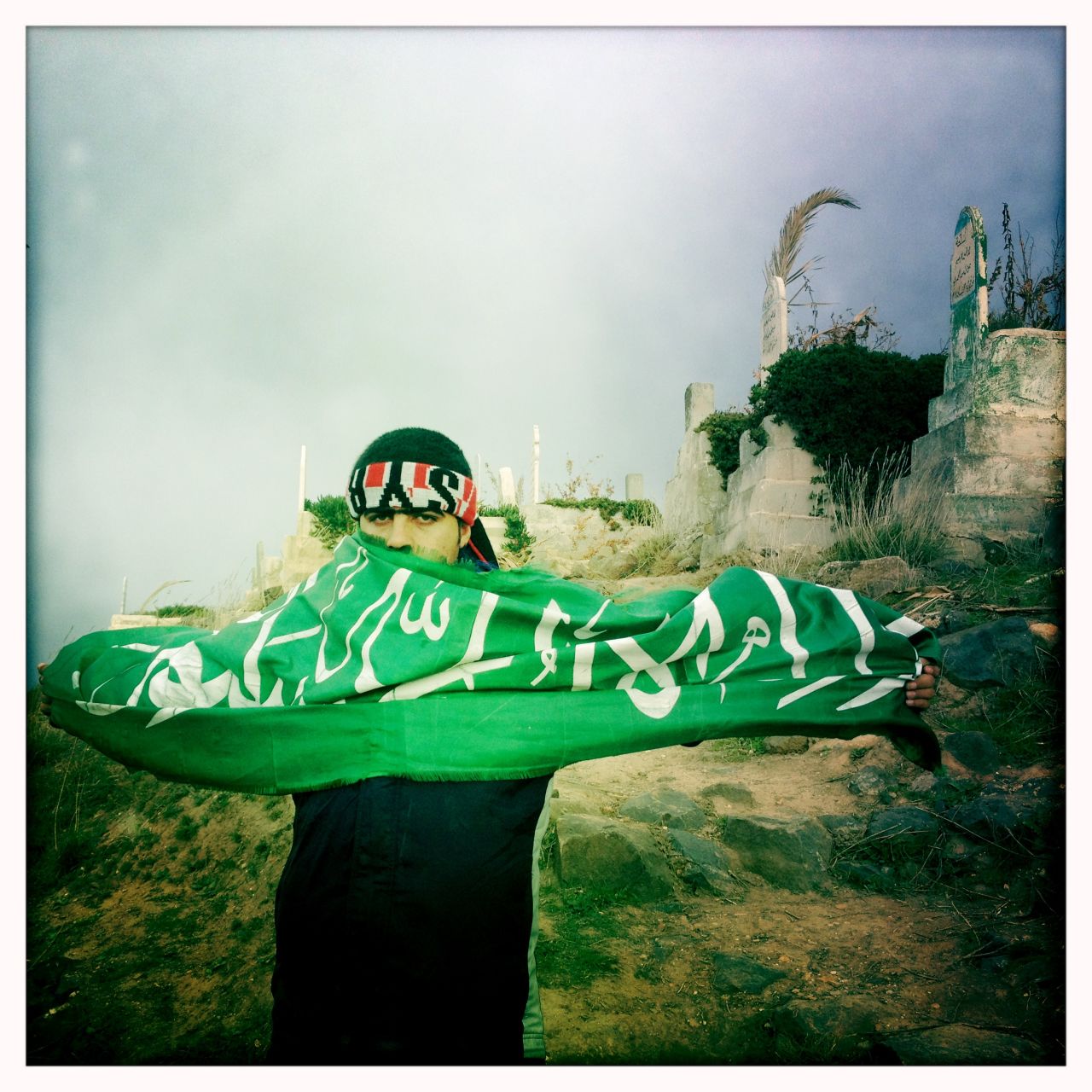 A mourner holds aloft a green flag with Islamic verses at the funeral of "Malik" in Dar al-Kabira.