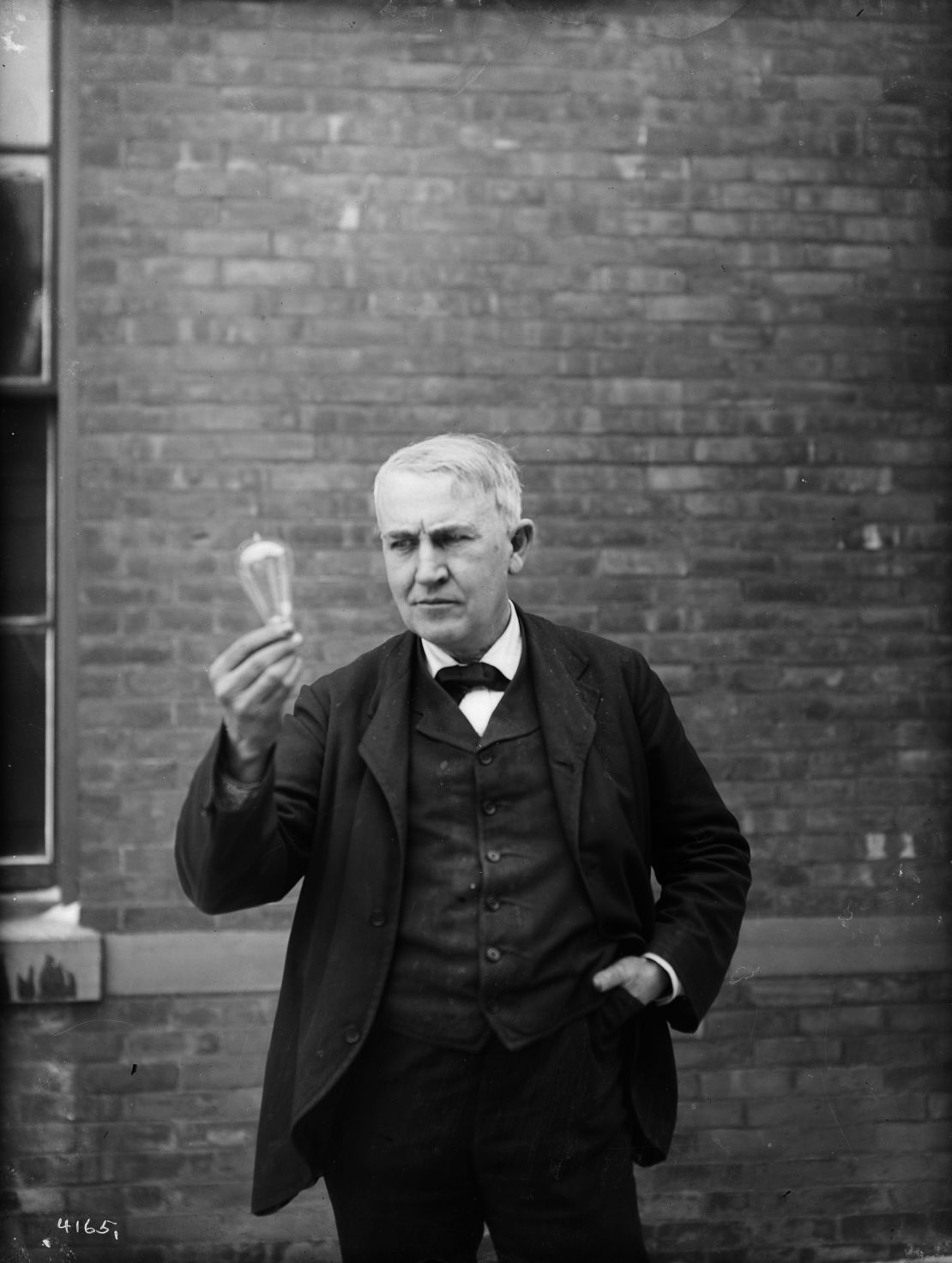 Inventor and physicist Thomas Alva Edison looking at a light bulb