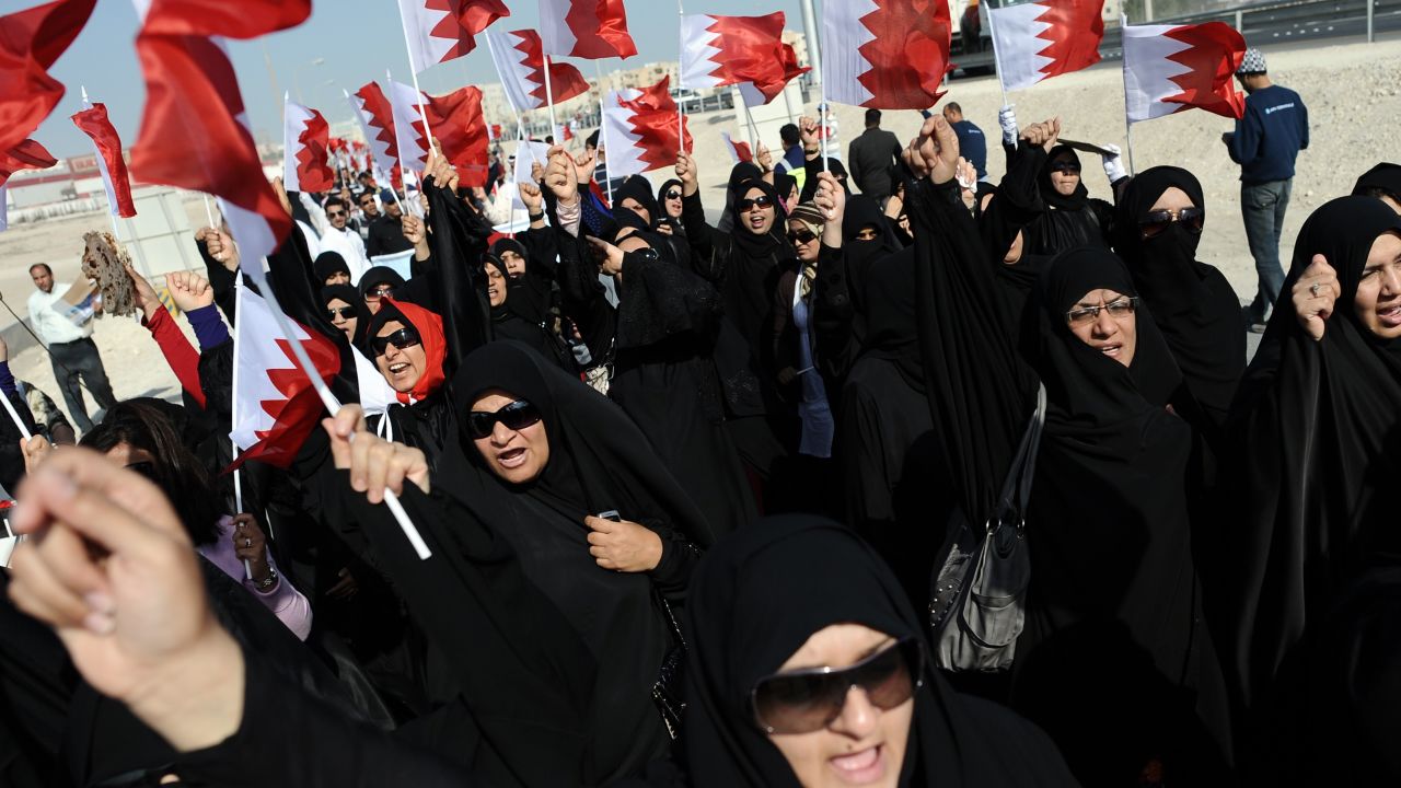 Women in Isa Town wave the Bahraini flag on Tuesday during a rally of Shiite workers who lost their jobs for protesting.