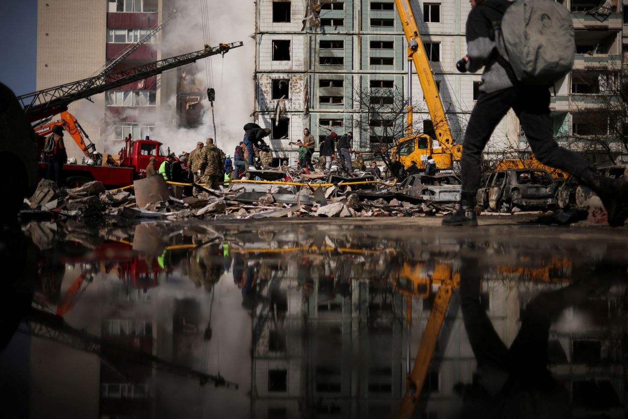 Local residents and rescuers stand amidst the rubble at the site of a heavily damaged residential building hit by a Russian missile in the town of Uman on Friday.