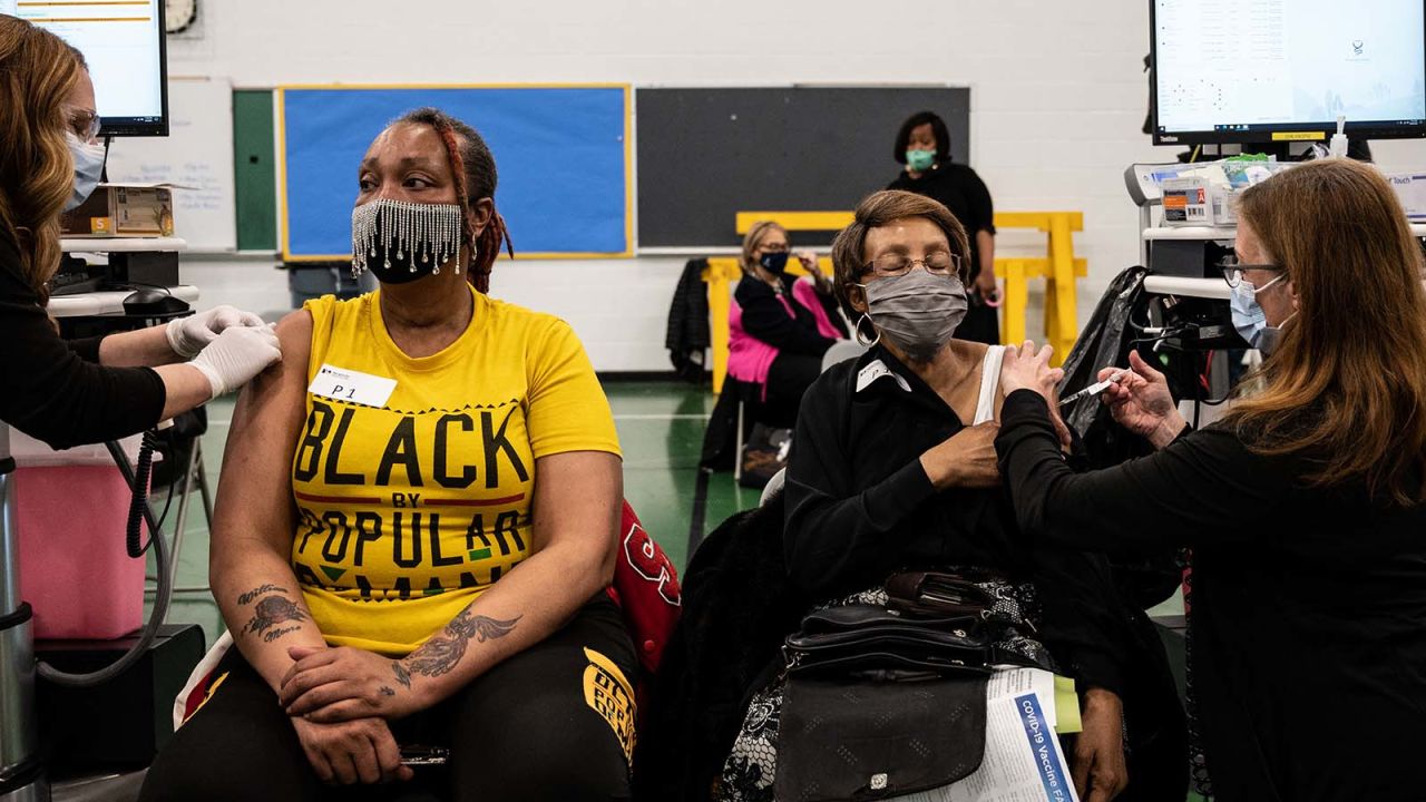 Andrea Moore sits as her mother, Alma Penn receives her Covid-19 vaccine in the gymnasium at Whitney M. Young Elementary School on April 2 in Louisville, Kentucky. 
