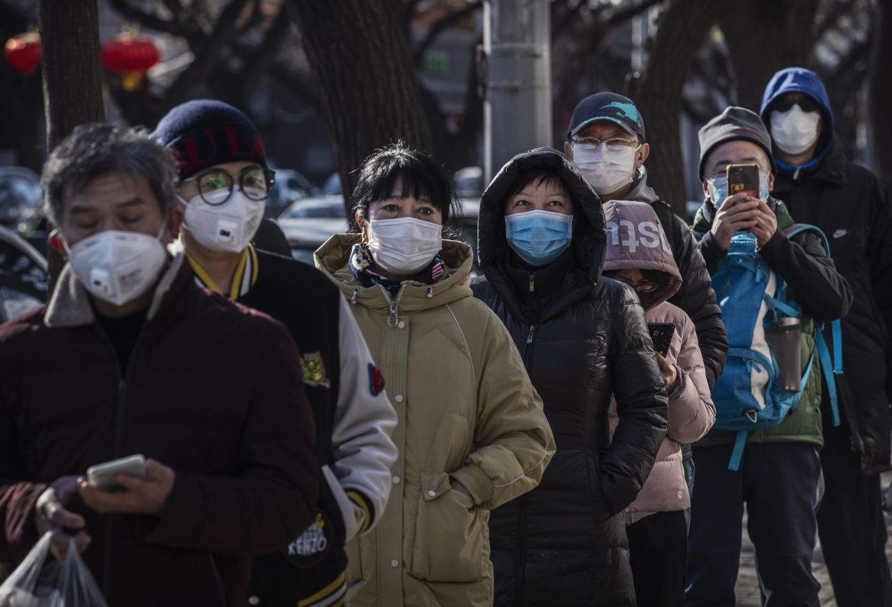 Chinese customers wear protective masks as they line up to buy dumplings at a shop on February 16, 2020 in Beijing, China. 