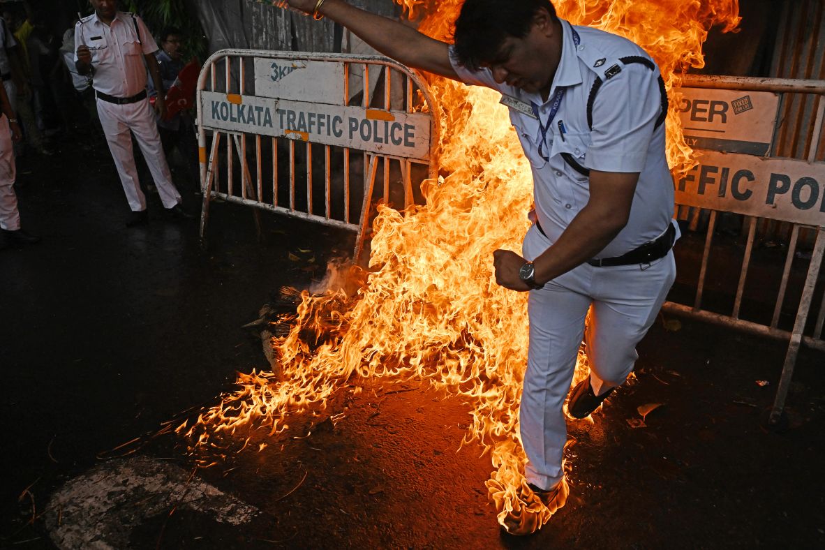 A police officer reacts after his shoes caught fire while trying to douse a fire set by activists in Kolkata, India, on Wednesday, July 9. The activists were burning an effigy of Prime Minister Narendra Modi during a nationwide strike called by trade unions to protest what they say are anti-worker policies.