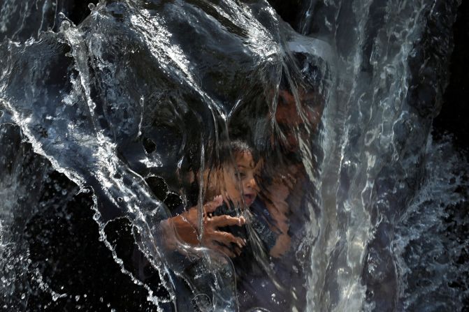 A man and a child cool off with canal water on a hot day in Peshawar, Pakistan, on Thursday, June 12.