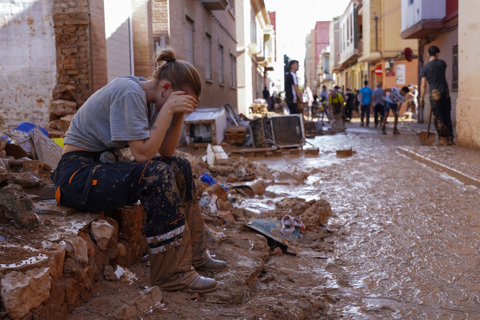 A woman rests as residents and volunteers clean up in Paiporta on Friday.