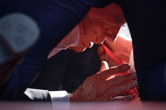 Blood can be seen on Trump's face as he is covered by Secret Service agents immediately after gunshots rang out in Butler on July 13.