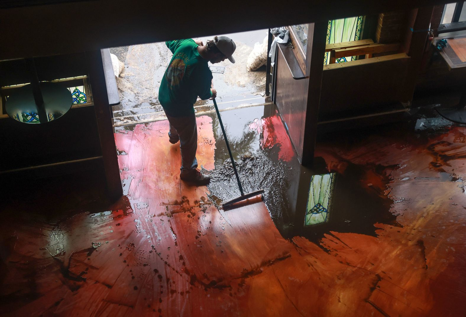 Austin Stolpe clears mud from the floor of the Celtic Ray Public House after it was inundated with floodwaters in Punta Gorda.