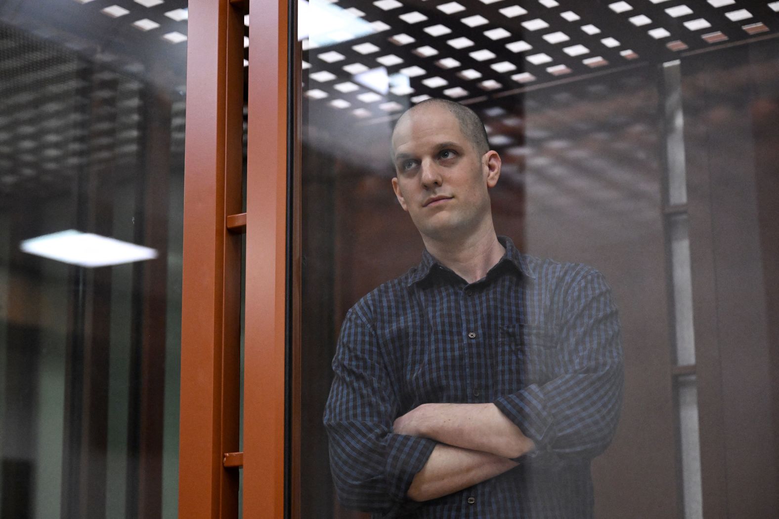 Evan Gershkovich, the first American journalist to be arrested on espionage charges in Russia since the Cold War, looks out from inside a courtroom’s glass cage before <a href="index.php?page=&url=https%3A%2F%2Fwww.cnn.com%2F2024%2F06%2F26%2Feurope%2Fevan-gershkovich-trial-begin-russia-intl%2Findex.html">a hearing</a> in Yekaterinburg, Russia, on Wednesday, June 26. Gershkovich has been detained in Russia for over a year. The US government and his employer, the Wall Street Journal, have vehemently denied the charges against him.