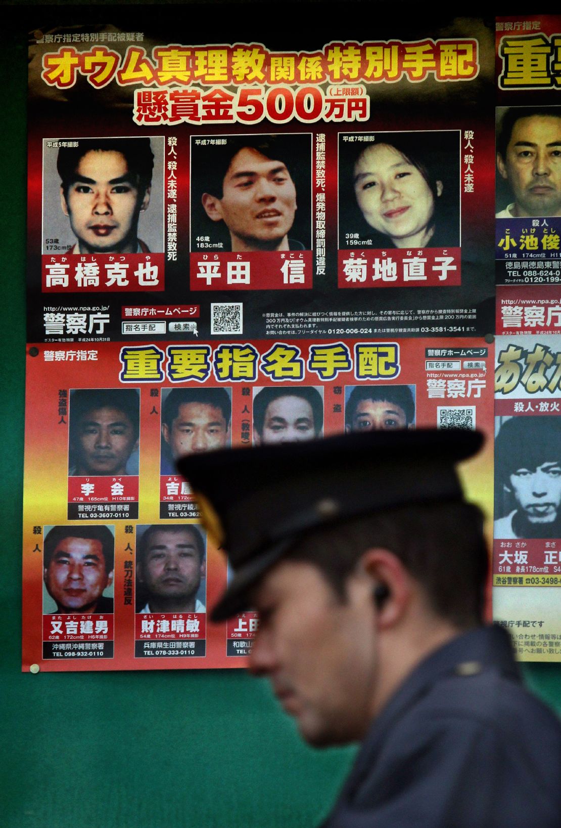 A policeman passes before pictures of suspected former members of Japan's Aum Supreme Truth doomsday cult, including Makoto Hirata who was arrested in Tokyo on January 1, 2012 after almost 17 years on the run.
