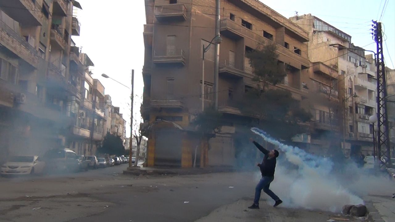 A protester in the flahspoint Syrian city of Homs throws a tear gas bomb back to security forces on December 27, 2011.