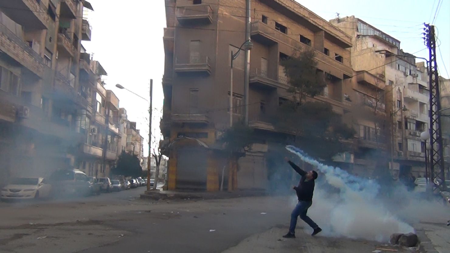 A protester in the flashpoint Syrian city of Homs throws a tear gas bomb back toward security forces last week.