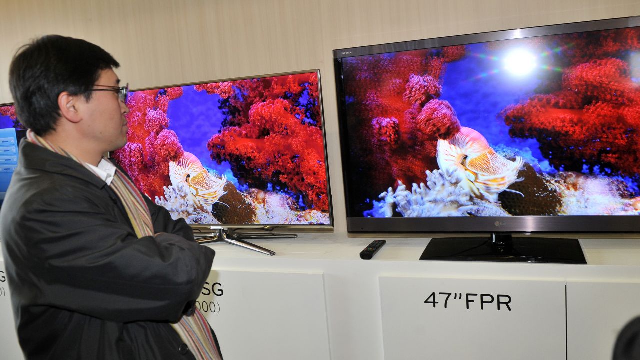A journalist compares the 3-D televisions of Samsung (L) and LG (R) after a news briefing in Seoul. 