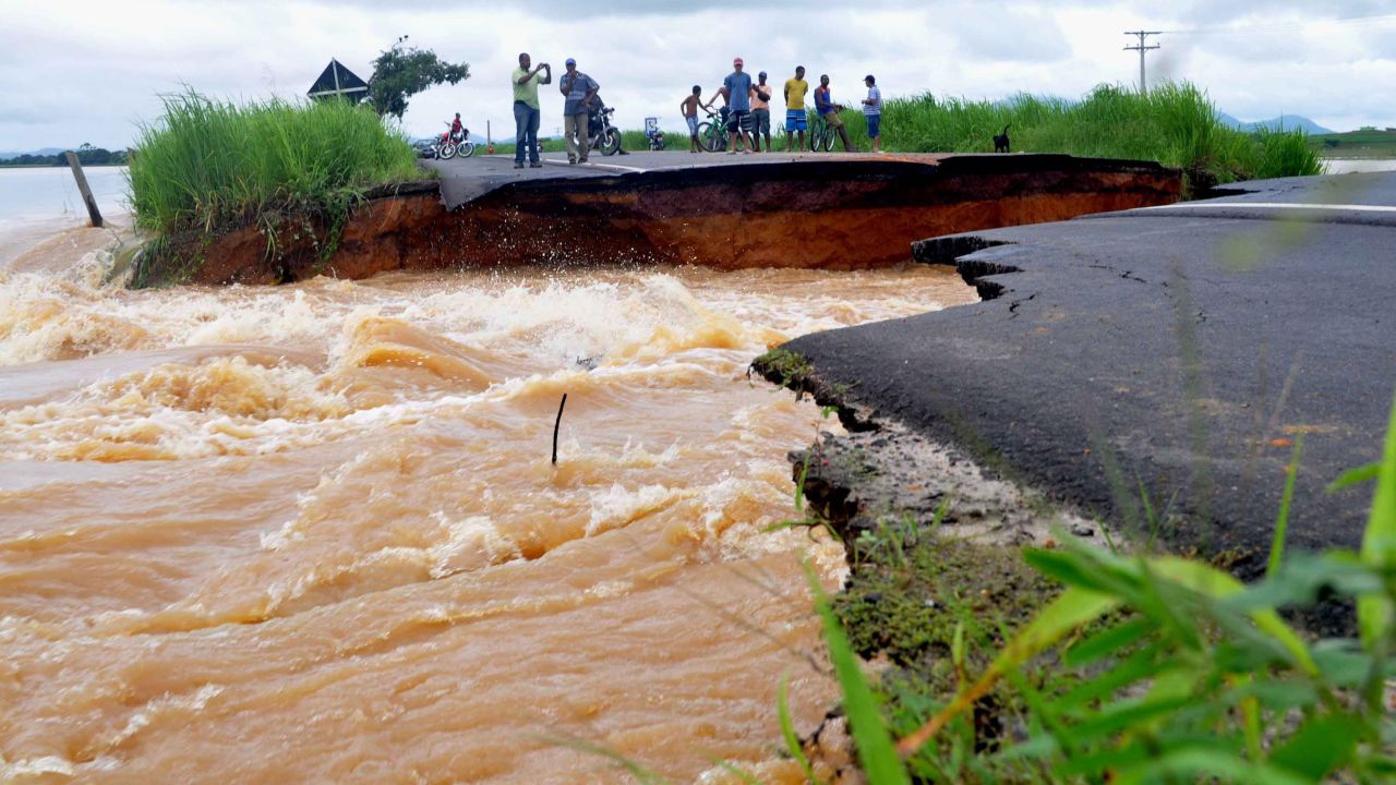 People watch water run through a washed-out road Thursday in Brazil's Rio de Janeiro state.