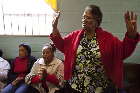 Co-op member Annie Bain sings for the group during a brief prayer service and business meeting before the food is distributed.