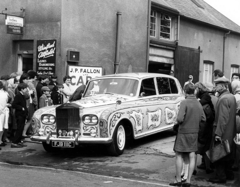 Two years on and psychedelia has taken hold. Here a crowd gathers to watch as John Lennon's Phantom V leaves the coachbuilders after its paint job. Rolls-Royce was reported to have disapproved of the color scheme.