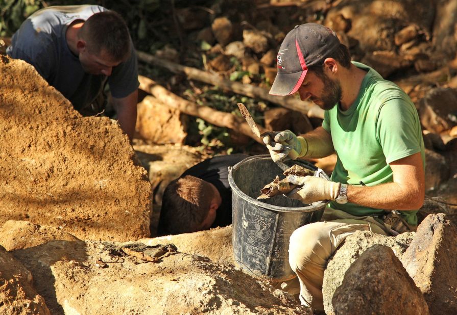 Sean Tallman, a Navy civilian and anthropologist from JPAC, examines items found beneath a boulder at a recovery site in Quang Nam Province, Vietnam.