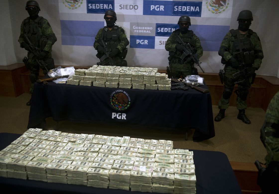 Soldados del ejército mexicano delante de un decomiso de más de 15 millones de dolares mostrado a la prensa el 22 de noviembre de 2011 en la Ciudad de México. El dinero fue incautado a presuntos miembros del cártel de Sinaloa, liderado por Joaquín Guzmán Loera, alias "El Chapo Guzmán".