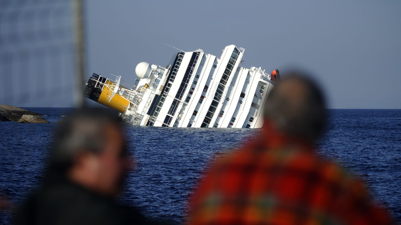 People look at the Costa Concordia after it ran aground and keeled over the Italian coast.