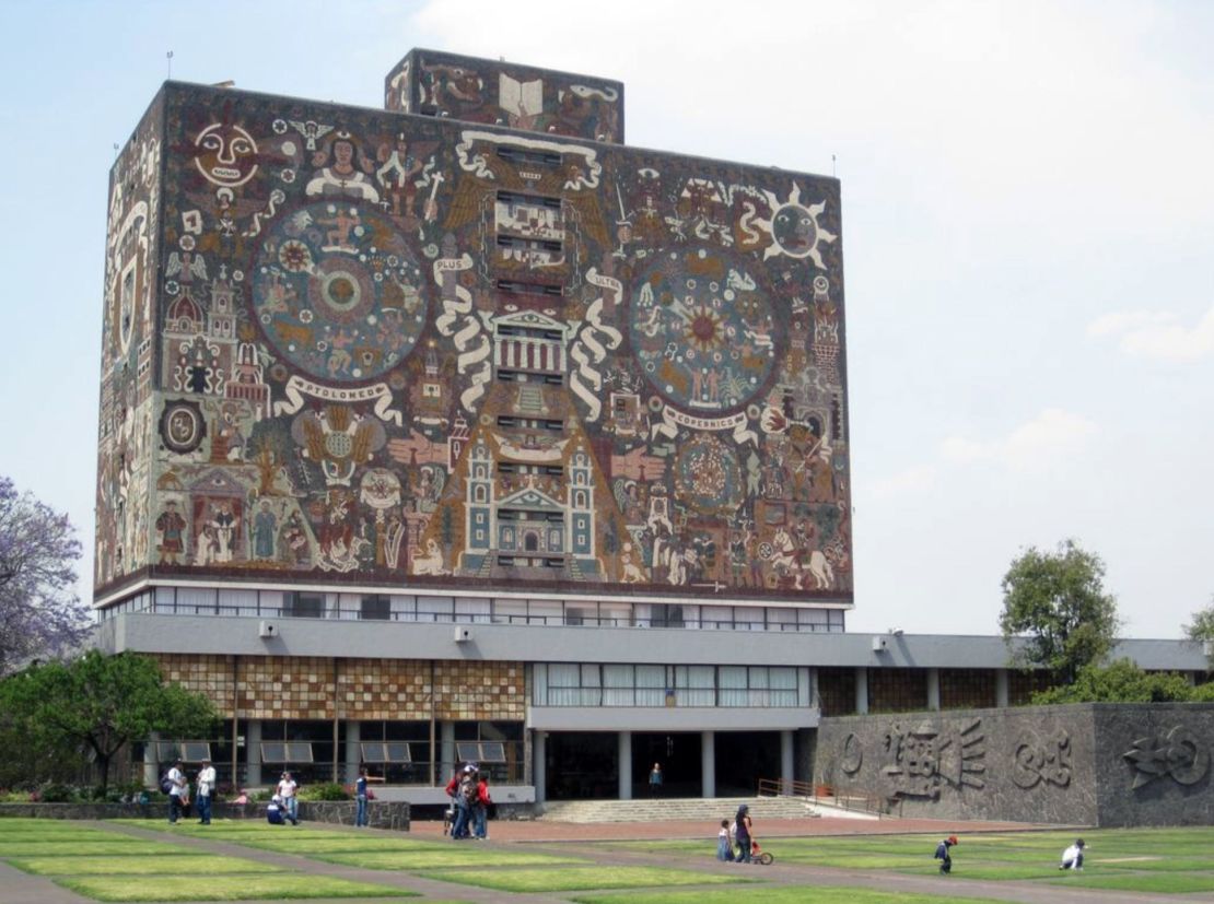 Students and families lounge on the grass outside the Central Library at the National Autonomous University of Mexico.