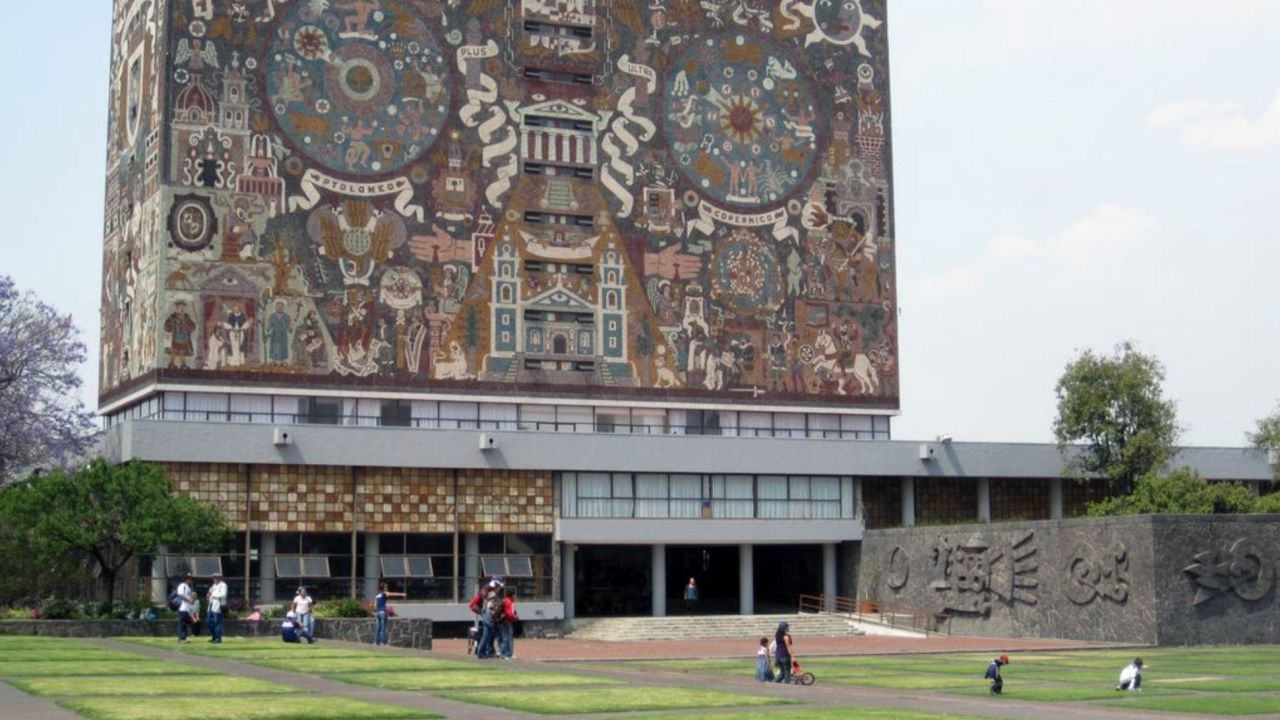 Students and families lounge on the grass outside the Central Library at the National Autonomous University of Mexico.