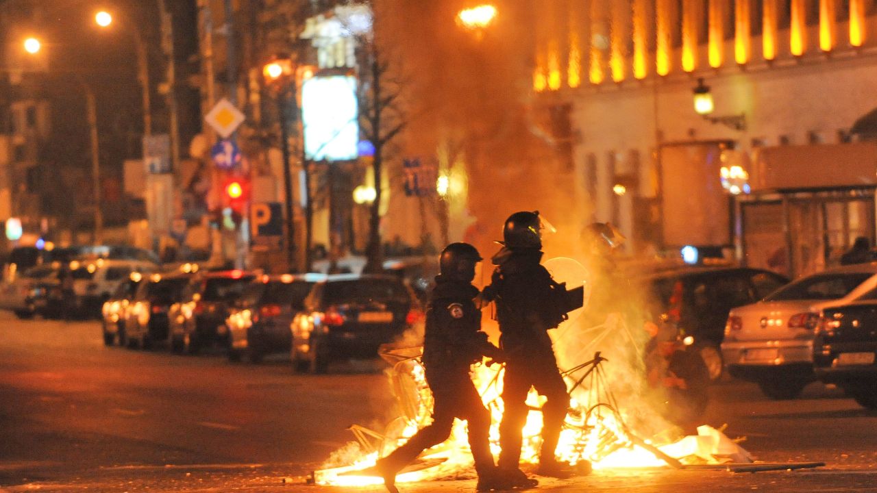 Romanian police walk past a fire lit by protesters in the center of Bucharest on January 15, 2012.