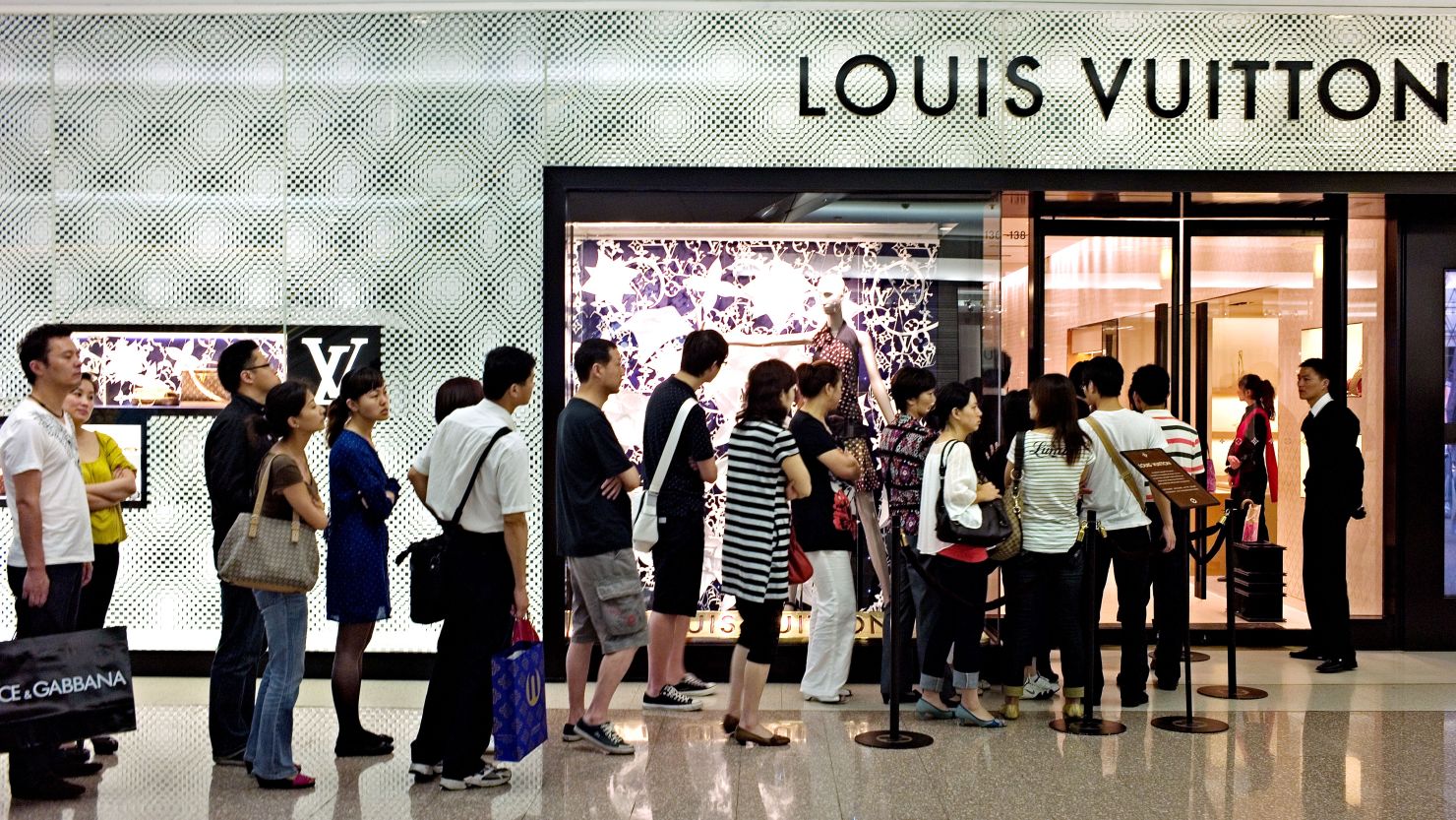 Shoppers queue to enter a shop of French luxury brand Louis Vuitton in a shopping mall in Shanghai, China. 