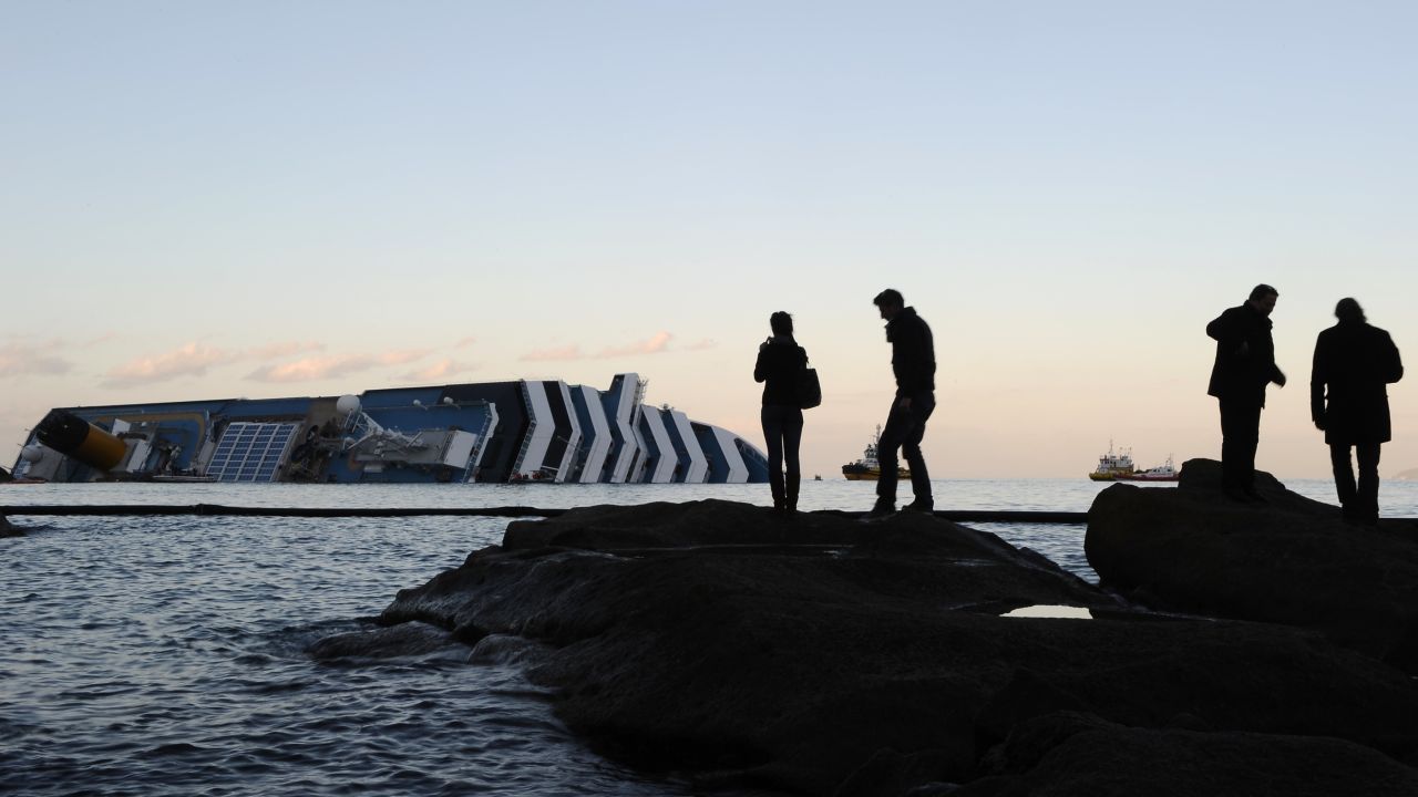People take pictures in front of the cruise liner Costa Concordia lying aground on January 20, 2012 in front of the harbour of the Isola del Giglio (Giglio island) after hitting underwater rocks on January 13.
