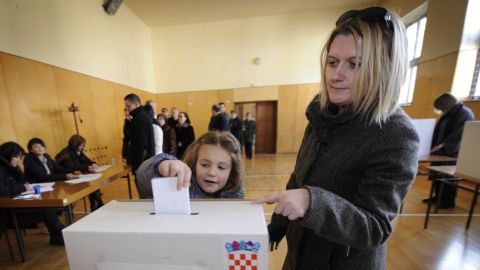 A Croatian girl casts her mother's ballot Sunday during the country's bid to join the European Union.