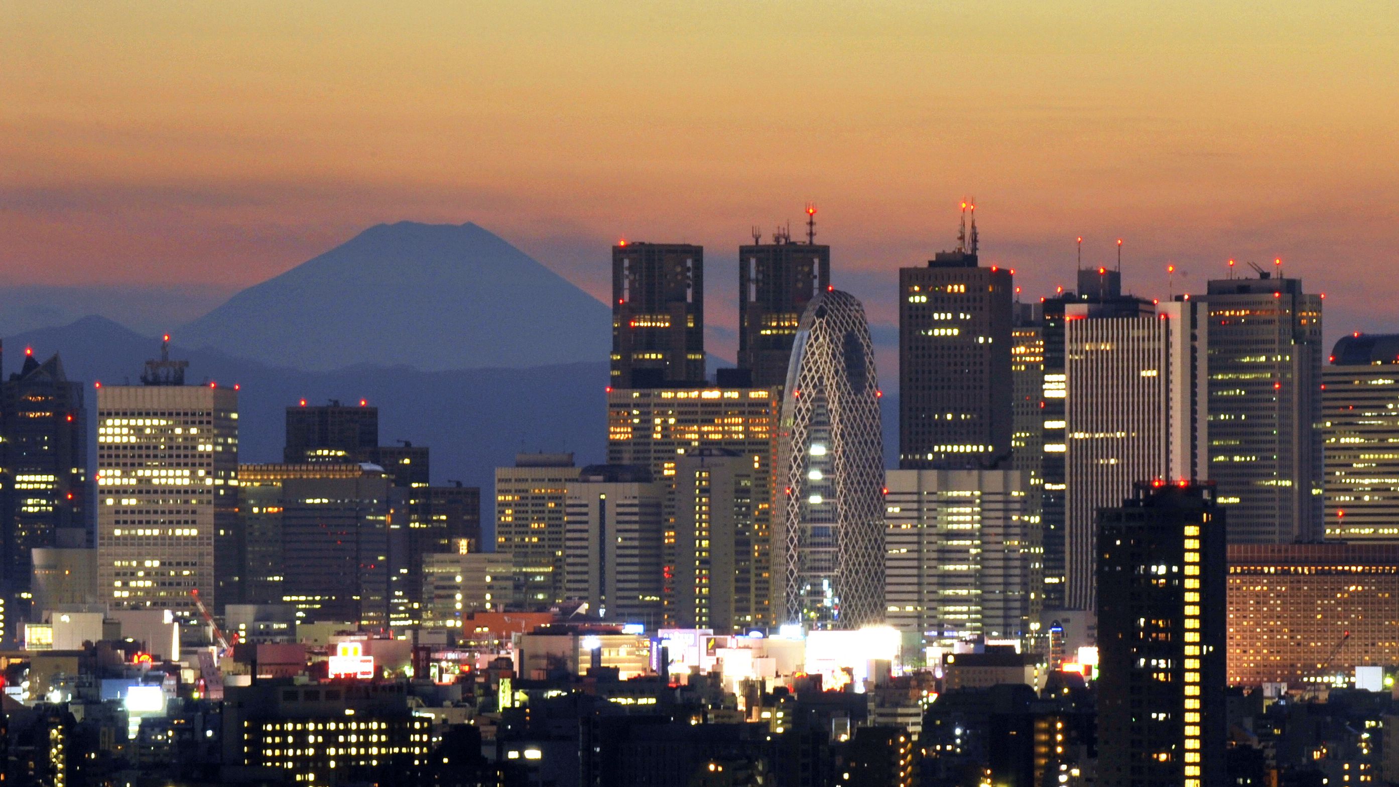 Japan's highest mountain, Mount Fuji, rises behind Tokyo's skyscraper skyline, as the sun sets in this photo last year.