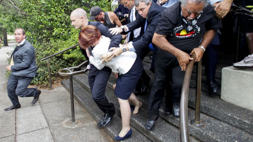 Australian Prime Minister Julia Gillard (C, white jacket) is bundled out of a restaurant by security service agents after it was surrounded by furious Aboriginal rights protesters in Canberra on January 26, 2012.   Gillard and opposition leader Tony Abbott were stranded in The Lobby restaurant as dozens of demonstrators from a protest against Australia Day, which marks the arrival of British settlers in 1788, converged on the hotel.    AUSTRALIA OUT  - NO ARCHIVES - NO INTERNET - RESTRICTED TO SUBSCRIPTION USE - RESTRICTED TO EDITORIAL USE  AFP PHOTO / AAP / Lukas Coch (Photo credit should read LUKAS COCH/AFP/Getty Images)