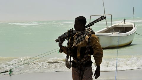  A Somali, part armed militia, part pirate, carries his high-caliber weapon on a beach in the central Somali town of Hobyo last year.