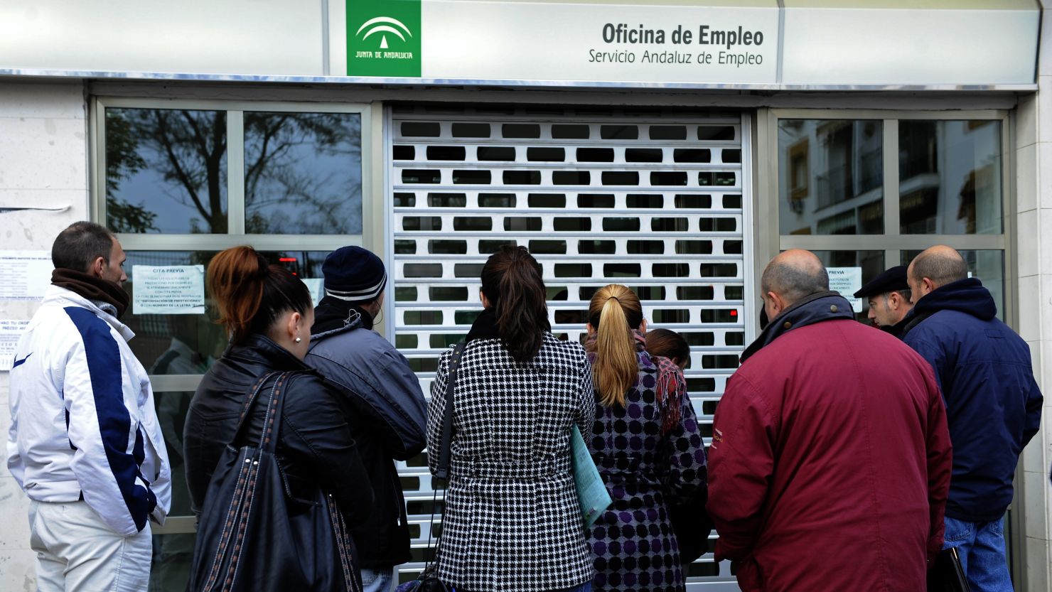 People wait in line in front of a government employment office in Sevilla, Spain, on Friday.