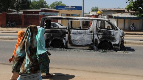 Young Nigerian girls walk past a vehicle burned in Damaturu, Yobe State, northeastern Nigeria, in November.