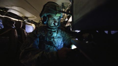 A U.S soldier checks his cell phone while on patrol in Iraq in December. Smartphones are first being deployed to soldiers.