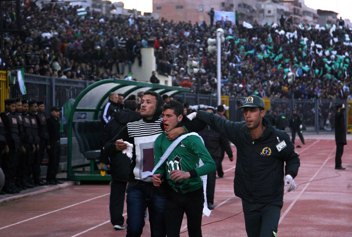 A wounded Al-Masry fan is escorted by a medic and a friend following the clashes.