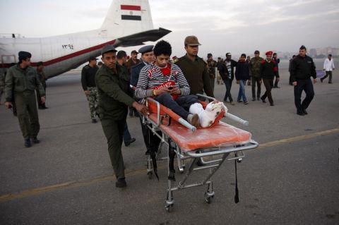 Egyptian soldiers help a wounded football Al-Ahly fan after he arrived in Cairo on a military plane.