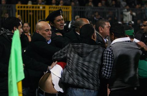 An Egyptian policeman intervenes as people try to separate rival football fans.