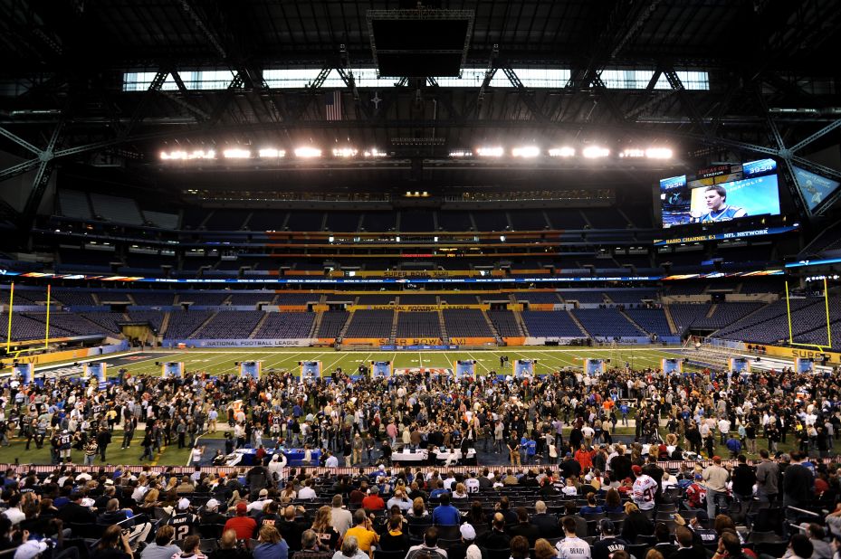 Fans gather at the Lucas Oil Stadium in Indianapolis, venue for the 46th Super Bowl, while the New England Patriots players address the media.