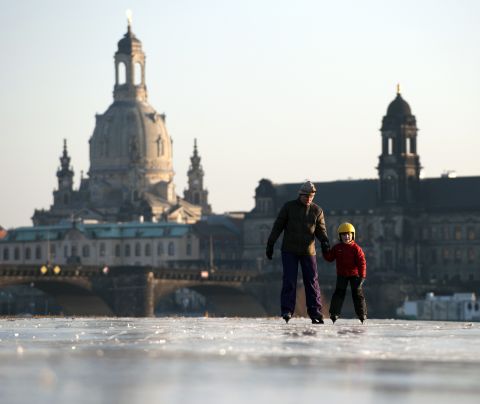 A boy and his mother skate on the partly frozen Elbe River on Thursday as the skyline of Dresden, Germany, is silhouetted in the background.