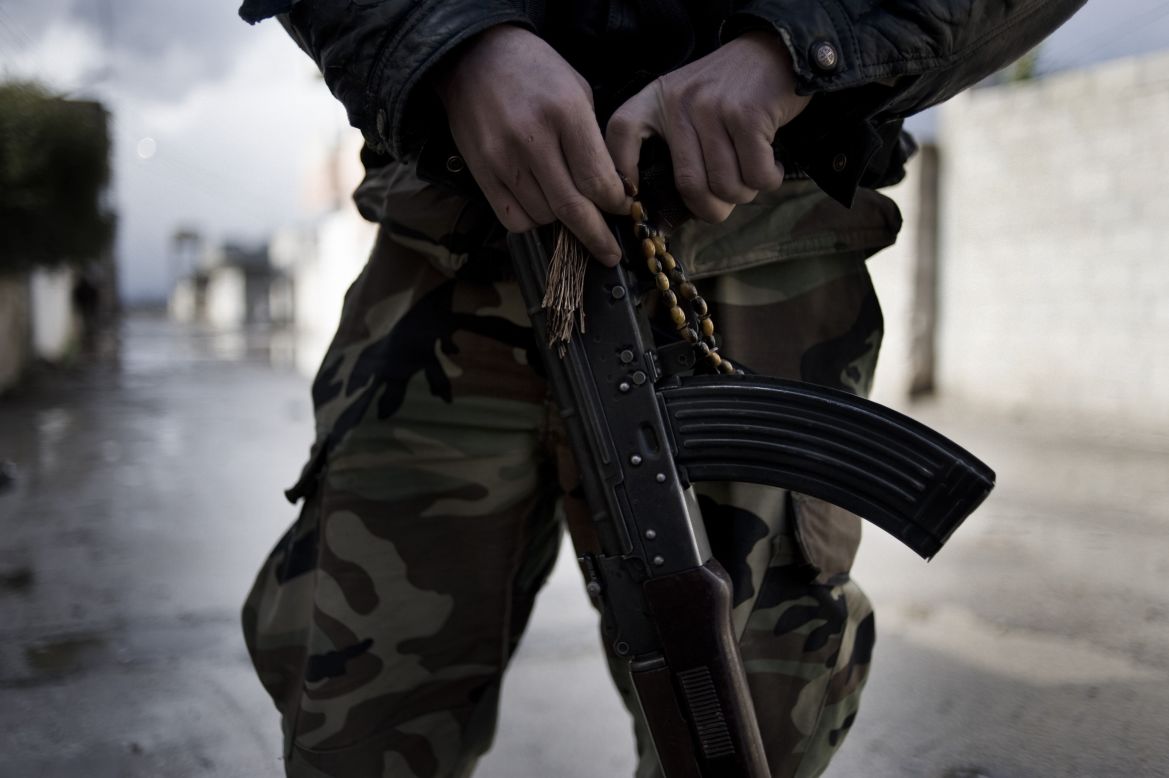 A member of the Free Syrian Army holds an AK-47 and prayer beads in the streets of Al-Qusayr.