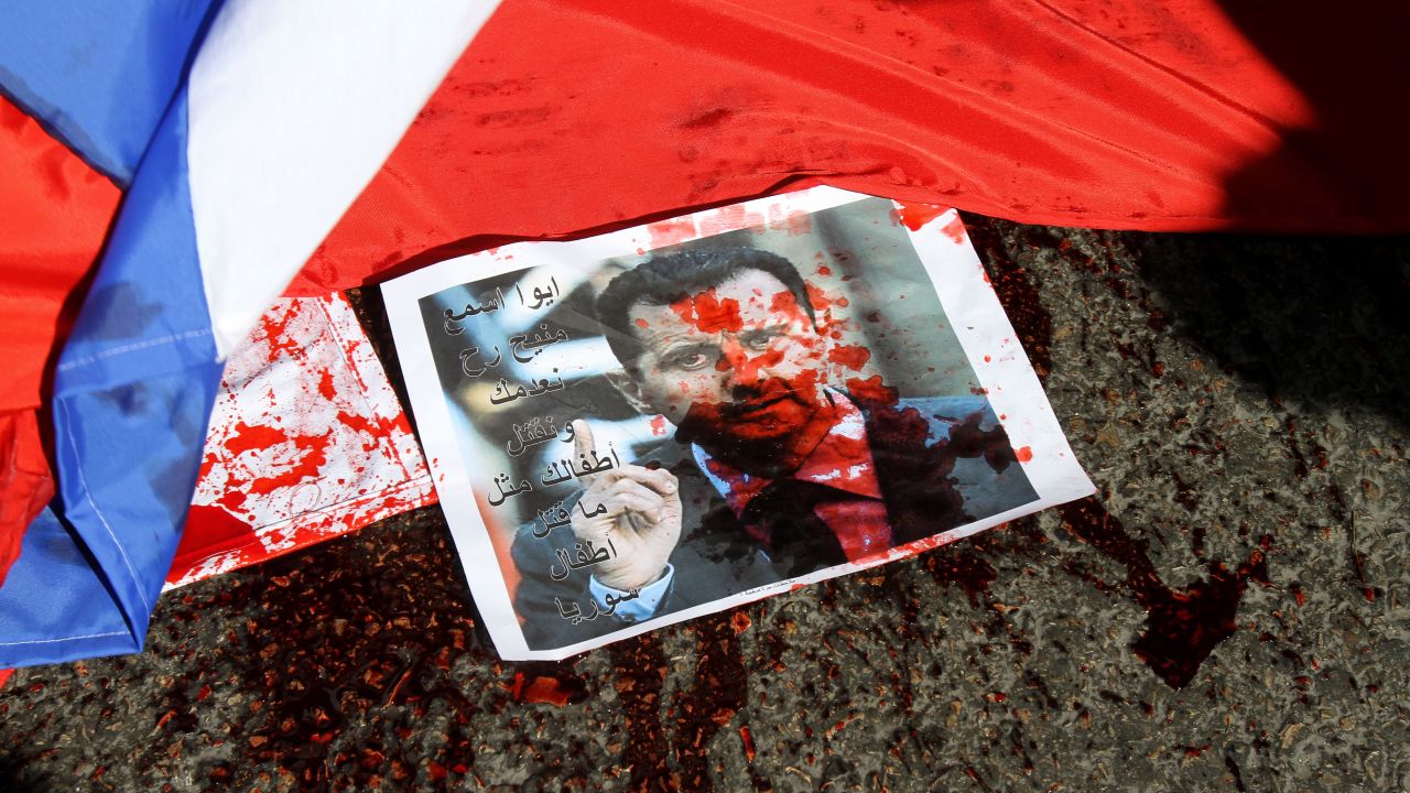A picture of Syria's embattled President Bashar al-Assad sprayed with red paint lies next to a Russian flag about to be set on fire by protesters outside the Russian embassy in Beirut on February 5.