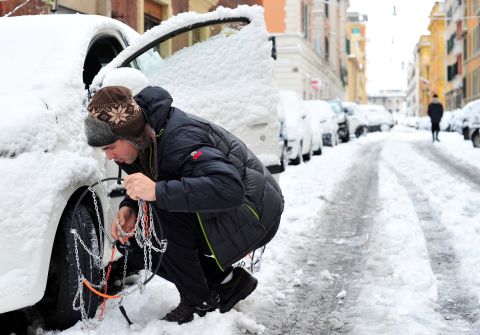 A man puts snowchains on his car Saturday in Rome. Heavy snowfall caused the Italian capital to grind to a halt. 