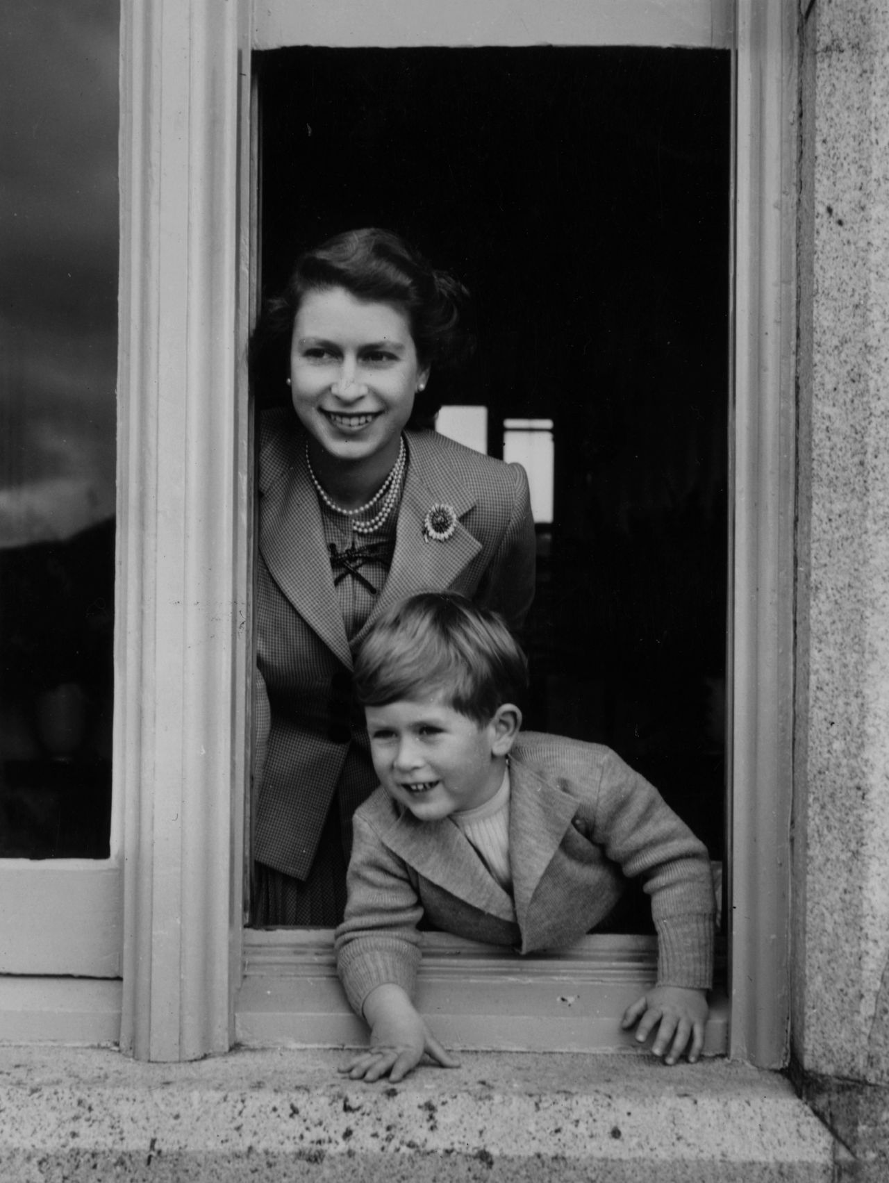 28th September 1952: Queen Elizabeth II and her son Charles leaning out of a window at Balmoral Castle, Scotland. 