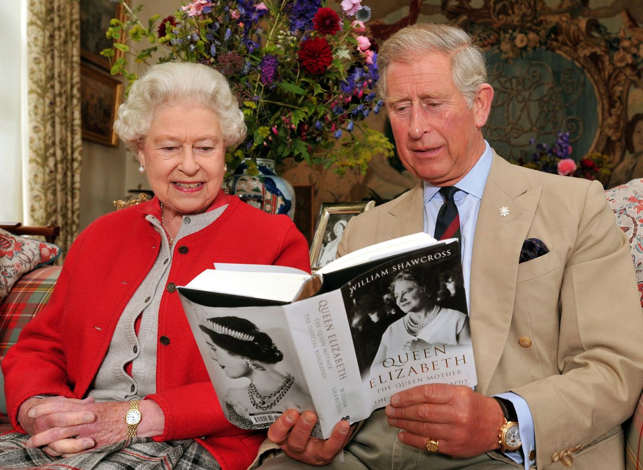 September 2, 2009: Queen Elizabeth II sits with the Prince Charles, and studies one of the first copies of ' Queen Elizabeth The Queen Mother, The Official Biography' in a living room at Birkhall the Scottish home of the Prince and Duchess of Cornwall.