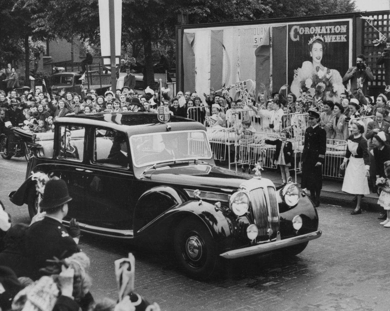 4th June 1953: Children wave as Queen Elizabeth II passes by in her car, at North Kensington, London.